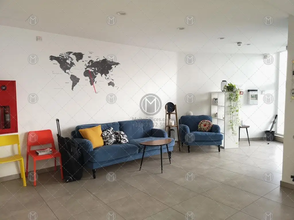 Lounge area with a blue sofa, armchair, world map wall art and colourful accent chairs